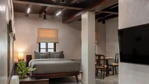 A modern bedroom with a large bed, bedside tables, a desk, and a TV. - Delhi House (Puducherry)