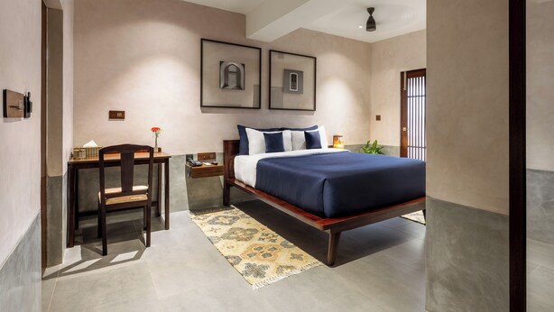 Un dormitorio con una cama, un escritorio y una silla. Hay dos cuadros en la pared.