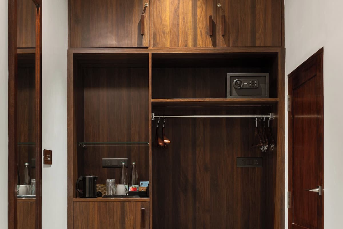 A walk-in closet with wooden shelving, a safe, and a coat rack.