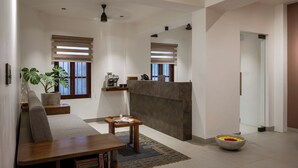 A spacious living area with a sofa, coffee table, and a bowl of flowers. - Delhi House (Puducherry)