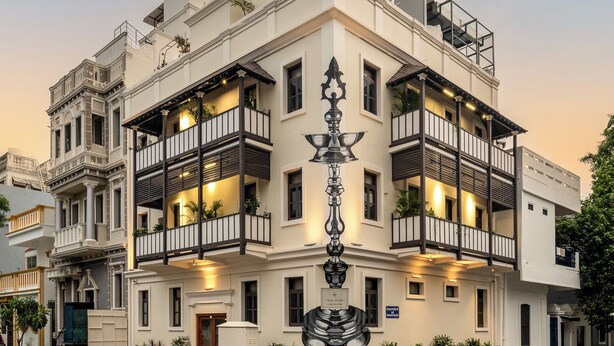 A multi-story hotel with balconies, a prominent entrance, and a decorative sign. - Delhi House (Puducherry)