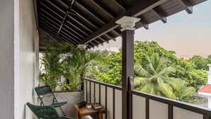 A balcony with two green chairs, a small table, and potted plants. - Delhi House (Puducherry)