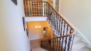 A staircase with a wooden handrail and black balusters, carpeted steps, and a chandelier. -  Hillside House , 18th century secluded country house with hot tub & gardens. (Dunfermline)