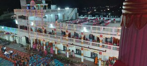 A multi-story building with balconies, a stage, and a crowd of people. - Hotel Karishma Palace Badnawar (Badnawar)