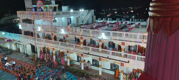 A multi-story building with balconies, a stage, and a crowd of people.