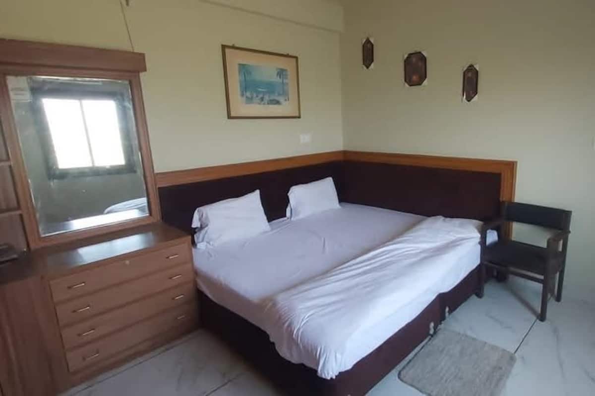 Un dormitorio con cama, armario de madera y una mesita.