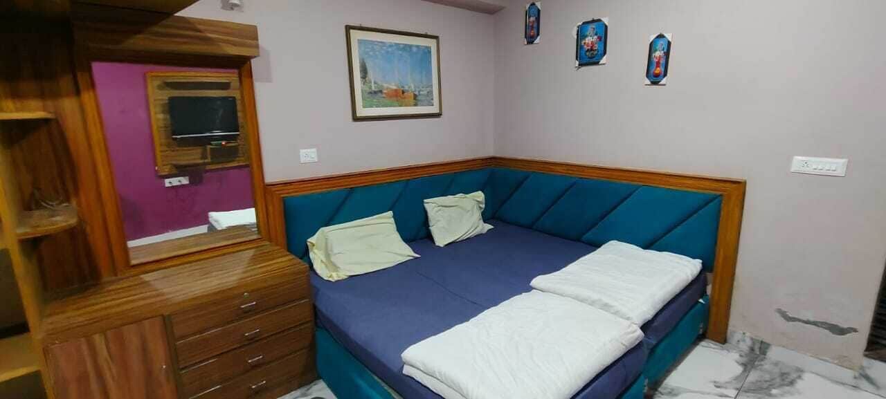 A bedroom with a bed, a wooden dresser, a mirror, and a painting on the wall.