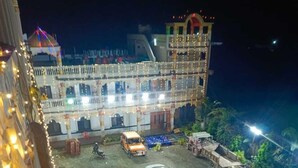 Un edificio de varios pisos con un balcón y un estacionamiento con varios coches.