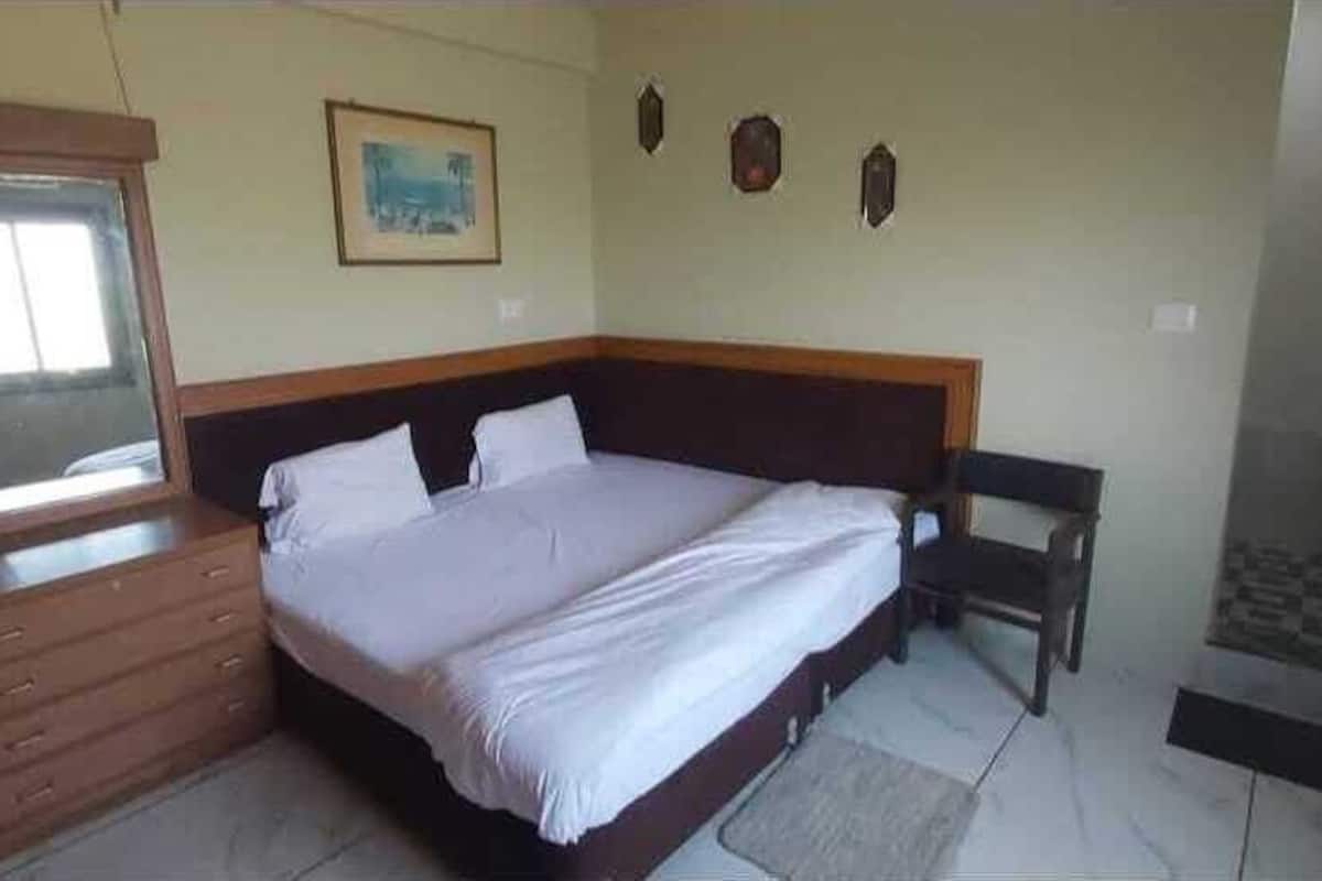 Un dormitorio con una cama, un armario de madera, una mesita pequeña y una estantería en la pared.