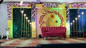 Un escenario con un sofá rojo, adornos florales y un fondo estrellado.