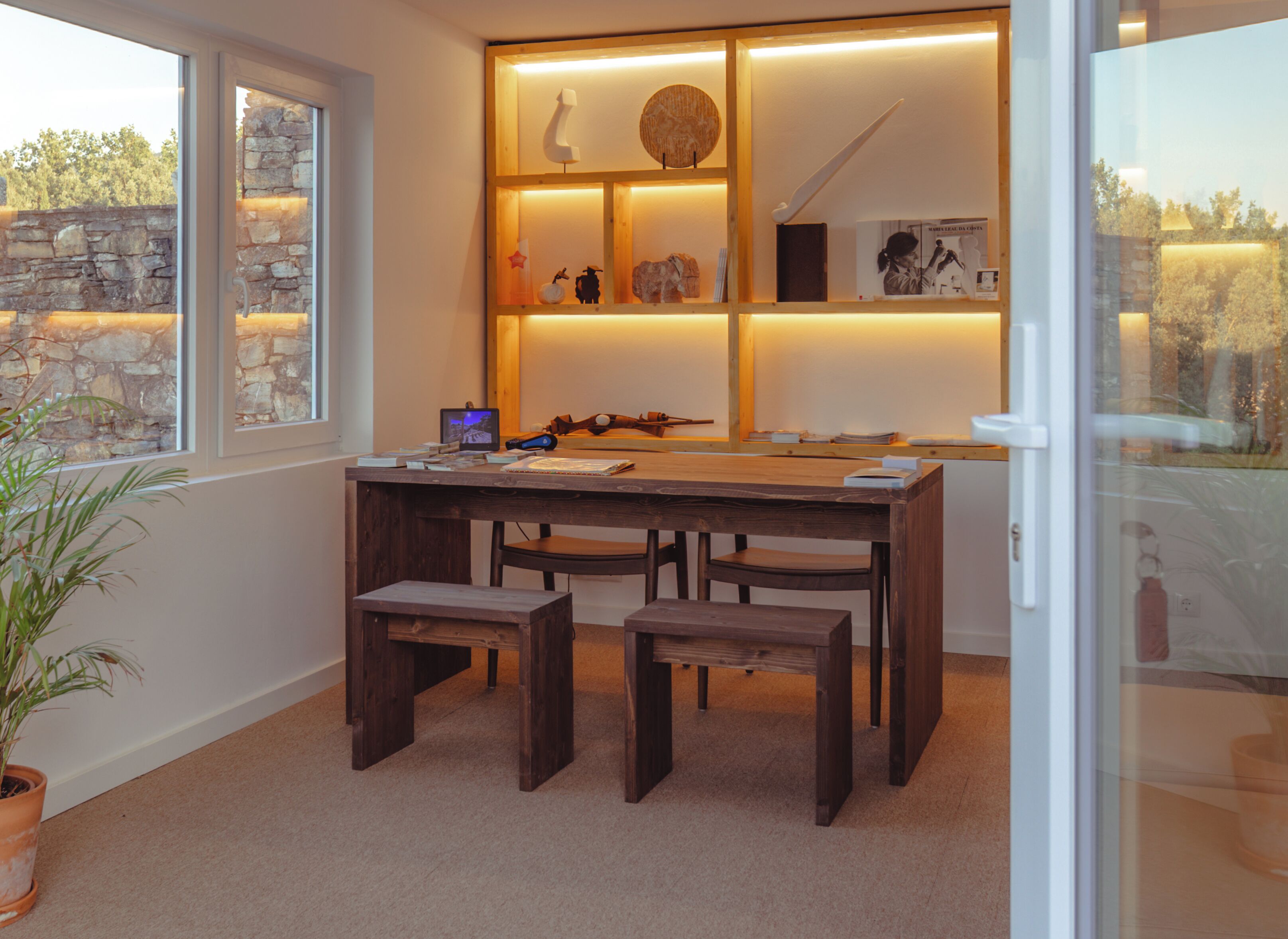A cozy room with a wooden desk, two chairs, and a bookshelf with various items.