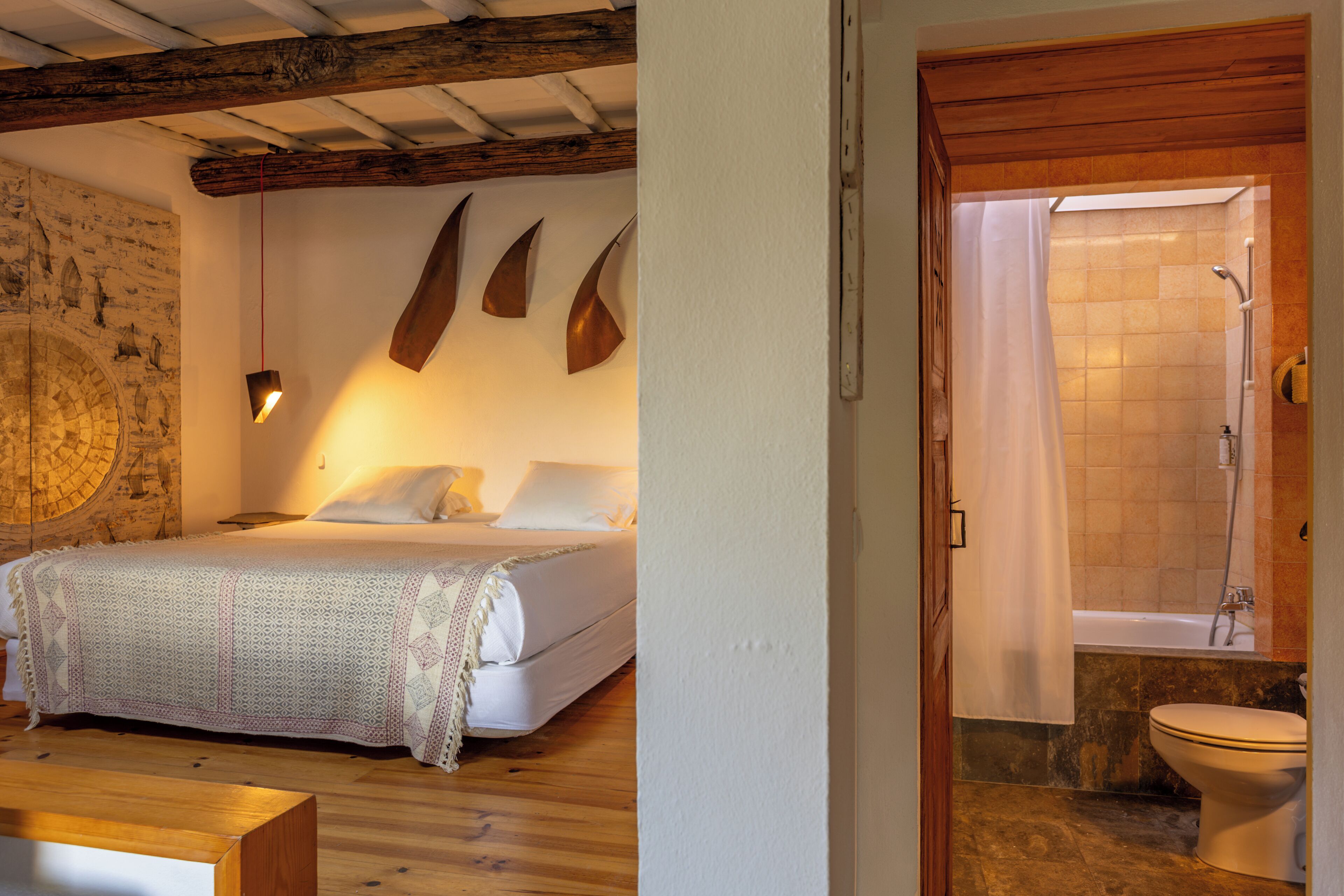 Un dormitorio con cama, techo de madera, un mapa en la pared y un baño con bañera e inodoro.