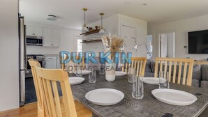 Un comedor moderno con una mesa de madera dispuesta para cuatro personas, platos blancos y vasos transparentes.