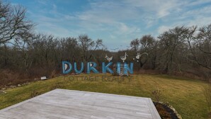 Una terraza de madera que lleva a un letrero que dice "DURKIN COTTAGE REALTY", adornado con aves decorativas y una cabaña rústica al fondo.