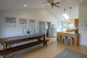 A modern kitchen with a central island, bar stools, a ceiling fan, and artwork on the walls. - Large Contemporary Home, Walk to Beach Central Air Conditioning, Spacious Deck (Narragansett)