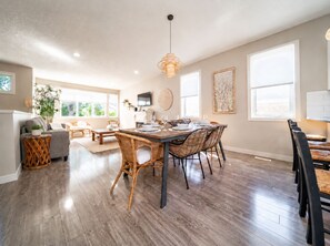 Un vaste espace de vie comprenant un coin repas avec une table pour quatre personnes, entourée de chaises en osier.