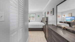 Quarto moderno com cama, cômoda, televisão e obras de arte nas paredes.