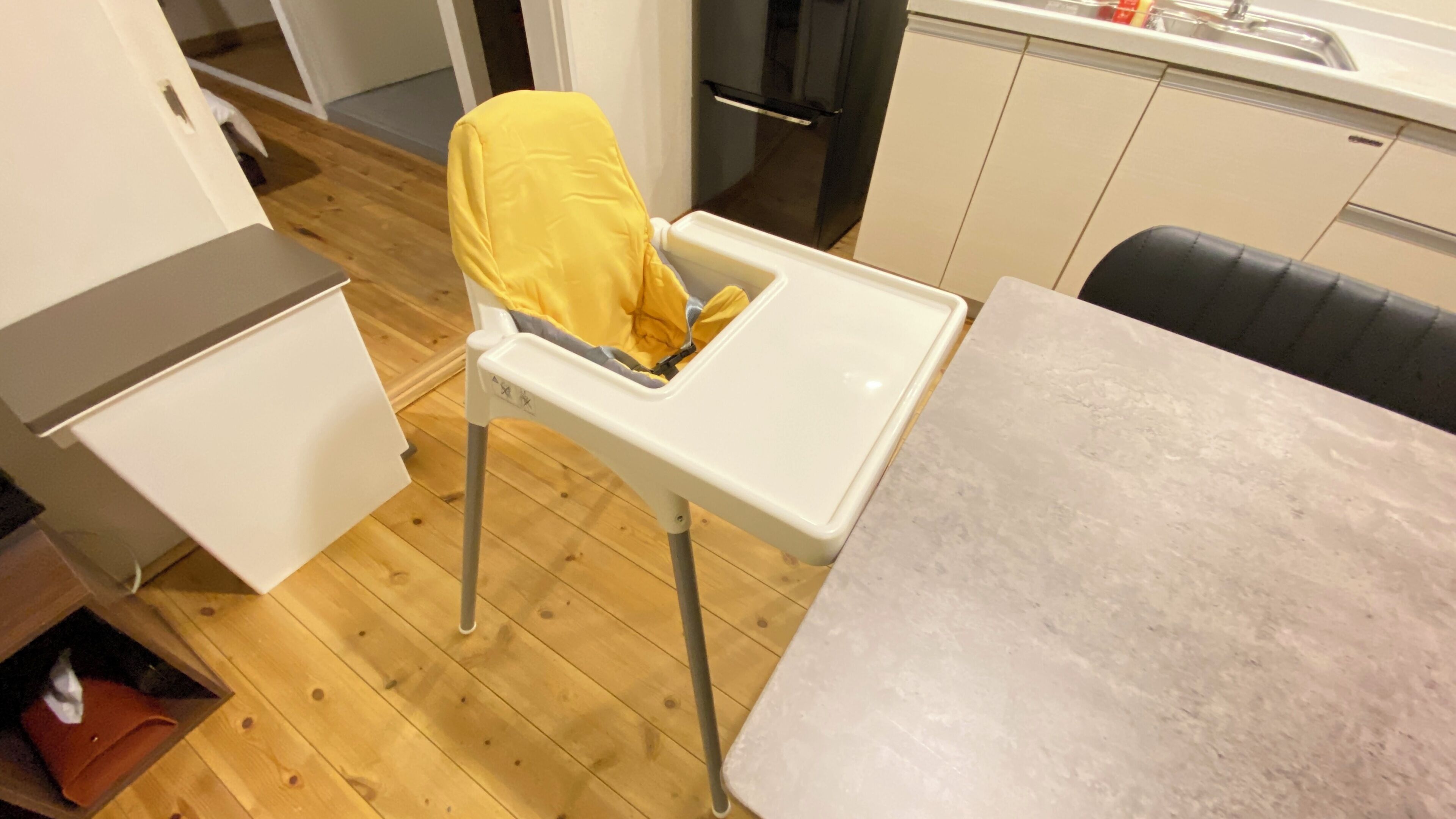 A kitchen with a white countertop, a small refrigerator, and a chair with a yellow cover.