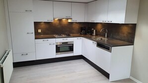 Una cocina moderna con armarios blancos, una encimera negra, horno empotrado y lavavajillas.