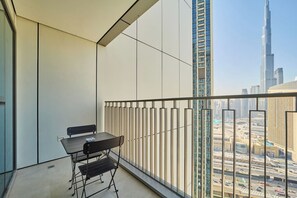 Un balcon avec une table et des chaises, offrant une vue sur un paysage urbain avec de hauts immeubles.