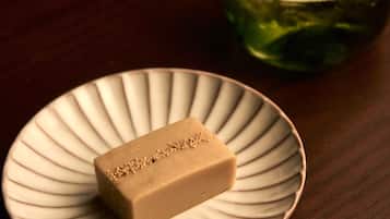 A rectangular bar of soap on a white plate with a ribbed edge, placed on a wooden surface.