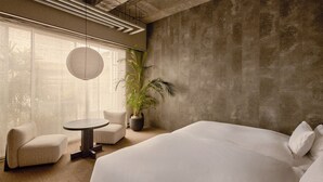 A modern hotel room with a large bed, two armchairs, a small round table, a potted plant, and a large window with a view. - KÚON Hakone Gora (Hakone)