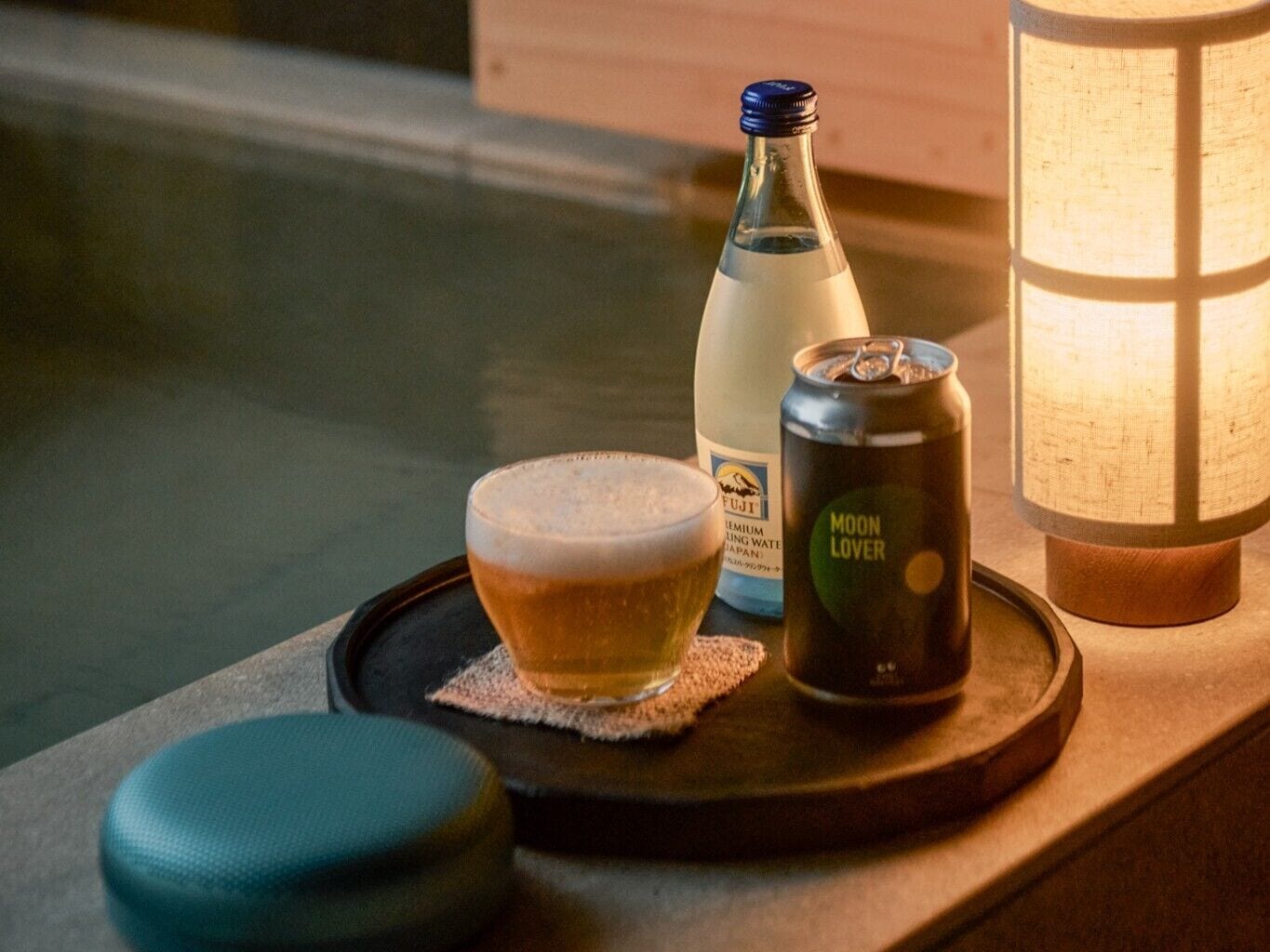 A glass of beer, a bottle of water, and a can of Moon Lover beer on a tray.