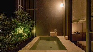 A modern bathroom with a rectangular bathtub, a small wooden stool, and a sink area. - KÚON Hakone Gora (Hakone)