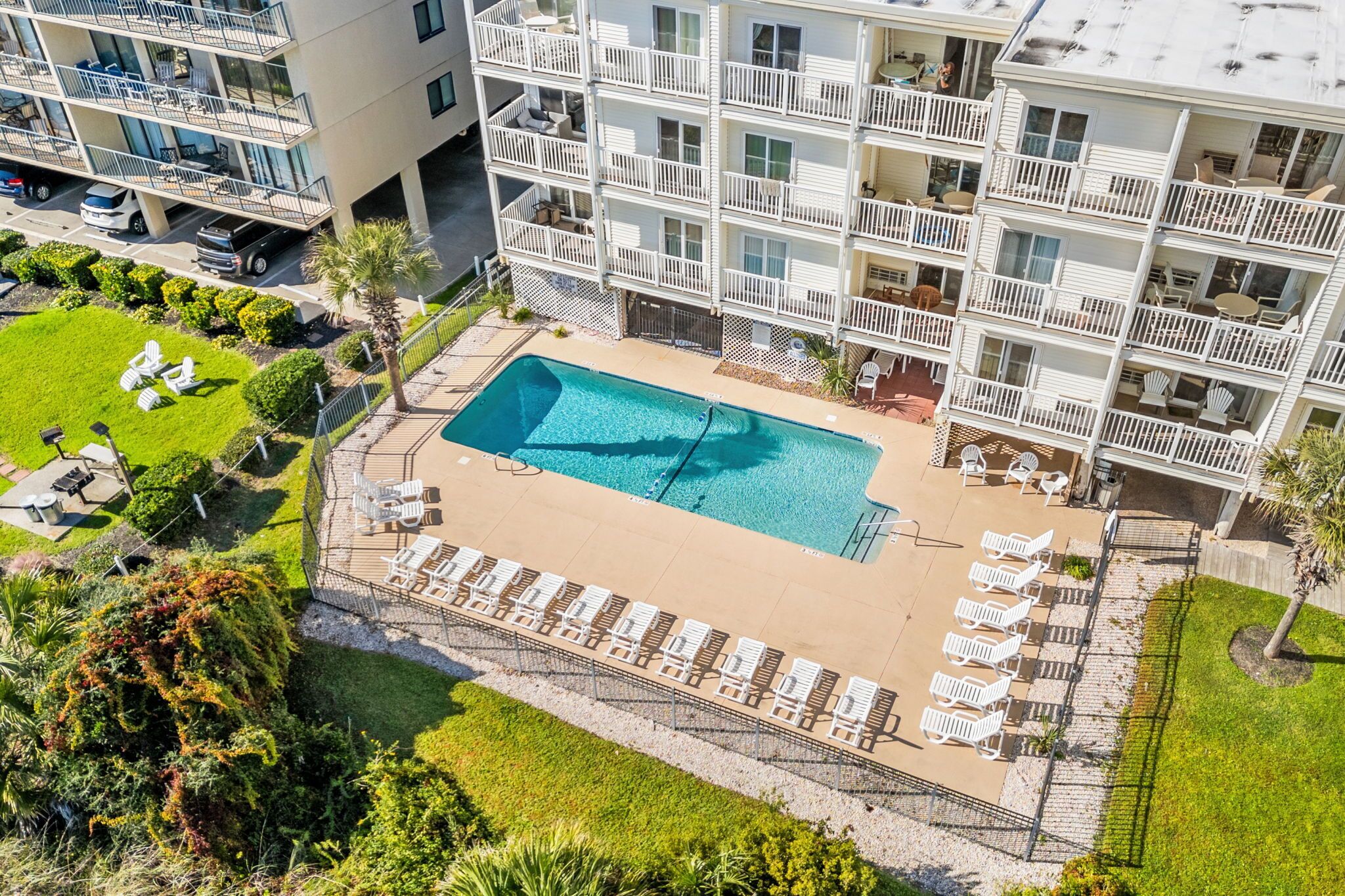 Un hôtel à plusieurs étages doté d’une piscine sur le toit, d’un espace extérieur aménagé et d’un jardin bien entretenu.