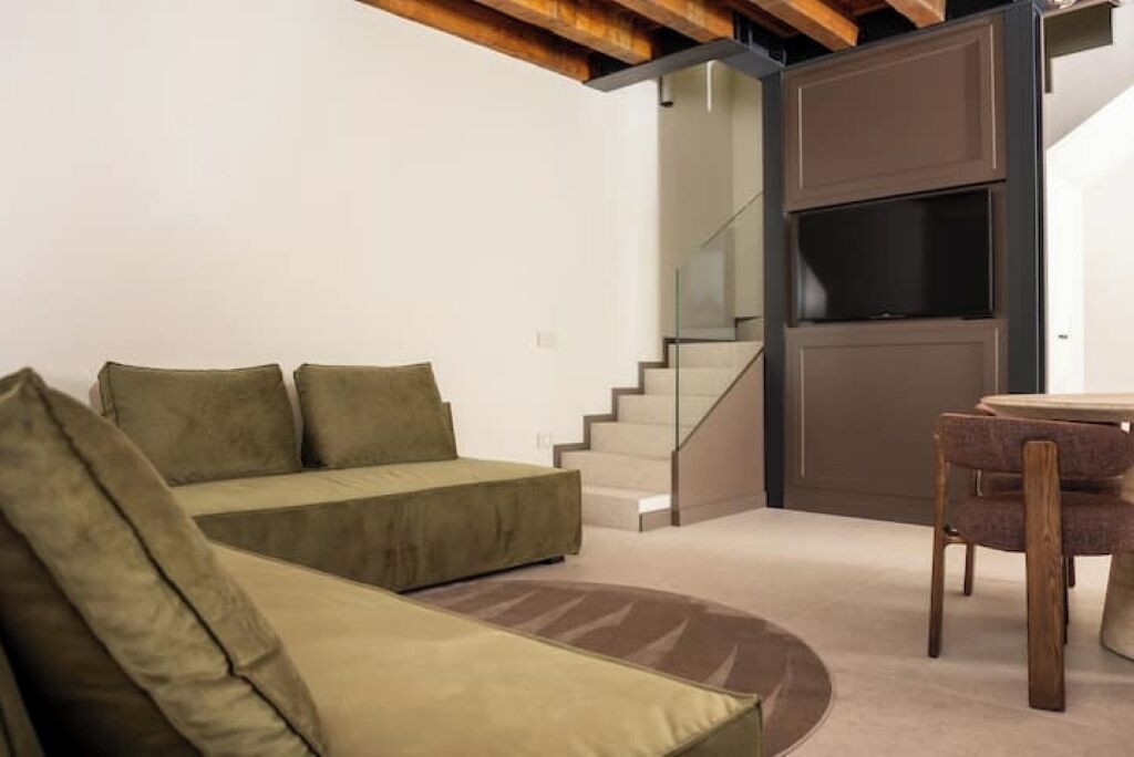 A modern living room with a sofa, a coffee table, and a staircase leading to a second floor.