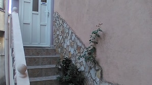 Una escalera con un muro de piedra en un lado y una puerta blanca en la parte superior.