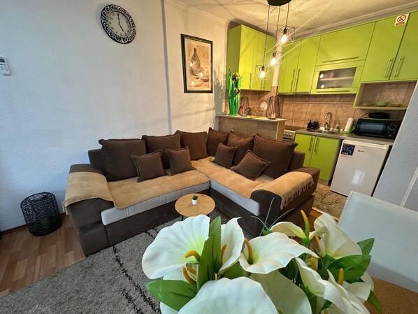 Una sala de estar con un sofá modular, una mesita de centro y una planta decorativa.