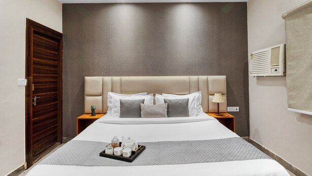 Ein Hotelzimmer mit einem großen Bett, zwei Nachttischen, einer Holztür und einer Wand-Klimaanlage.
