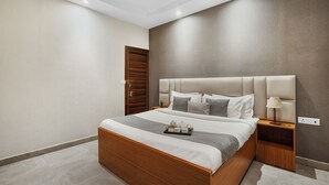 Ein modernes Schlafzimmer mit einem Holzbett, einem Nachttisch mit Lampe und einer Ablage mit Teeutensilien.
