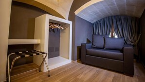 Una sala moderna con un sofá oscuro, un armario empotrado con ropa colgada y suelo de madera.