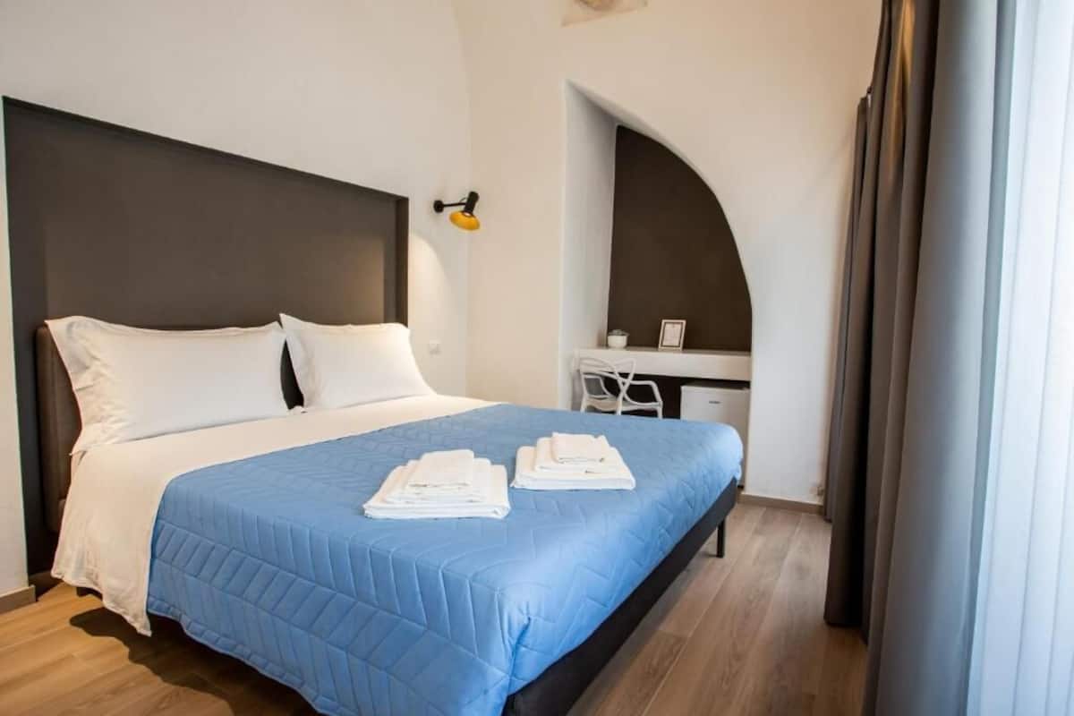 A hotel room with a bed, a desk, and a chair.