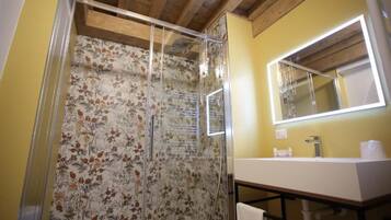 Un baño con ducha, lavamanos y espejo.