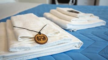 Des serviettes blanches, soigneusement pliées, sont empilées sur un couvre-lit bleu matelassé.