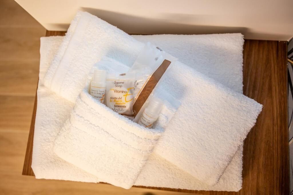 A white towel with toiletries including soap and lotion in a wooden room.