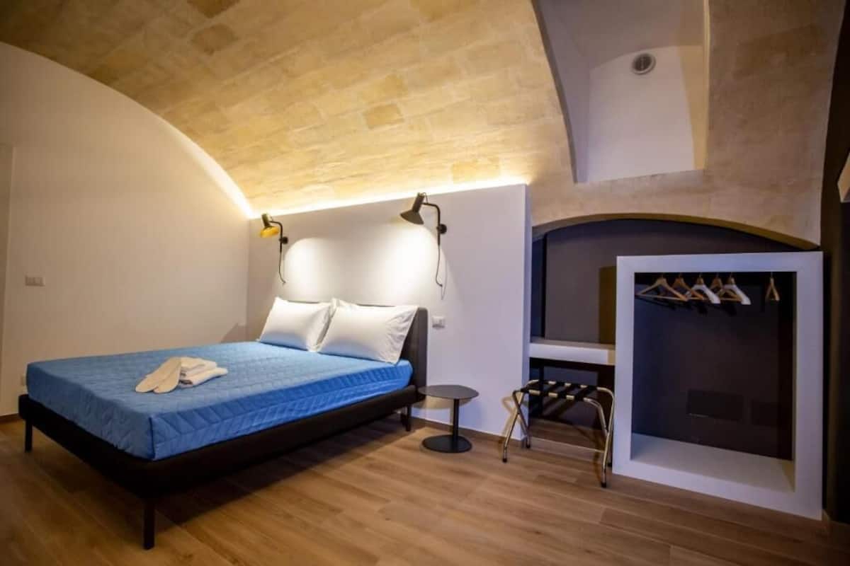 A bedroom with a bed, a small table, a chair, and a built-in wardrobe.