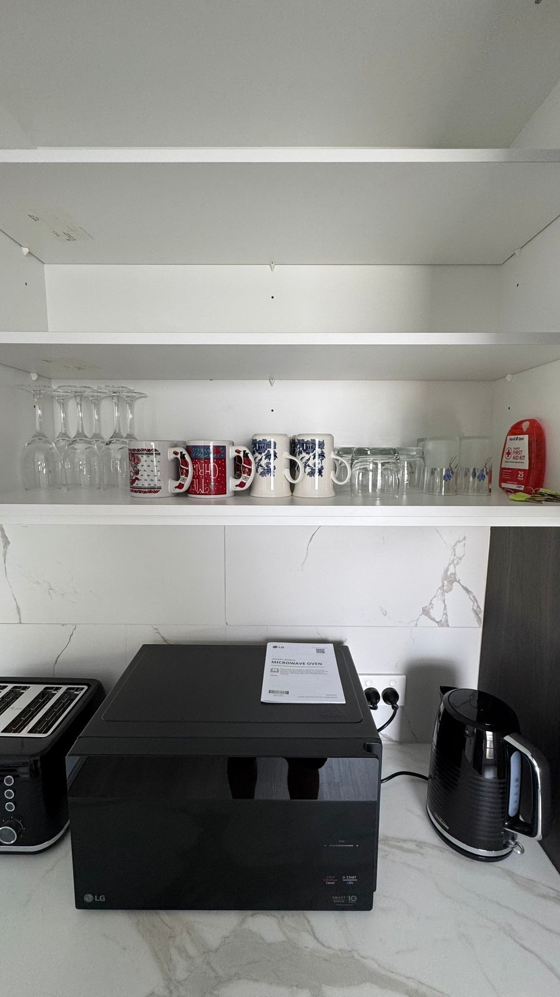 A kitchen with a microwave oven, a toaster, and a kettle on the counter.