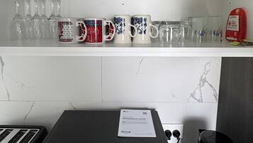 A kitchen with a microwave oven, a toaster, and a kettle on the counter.