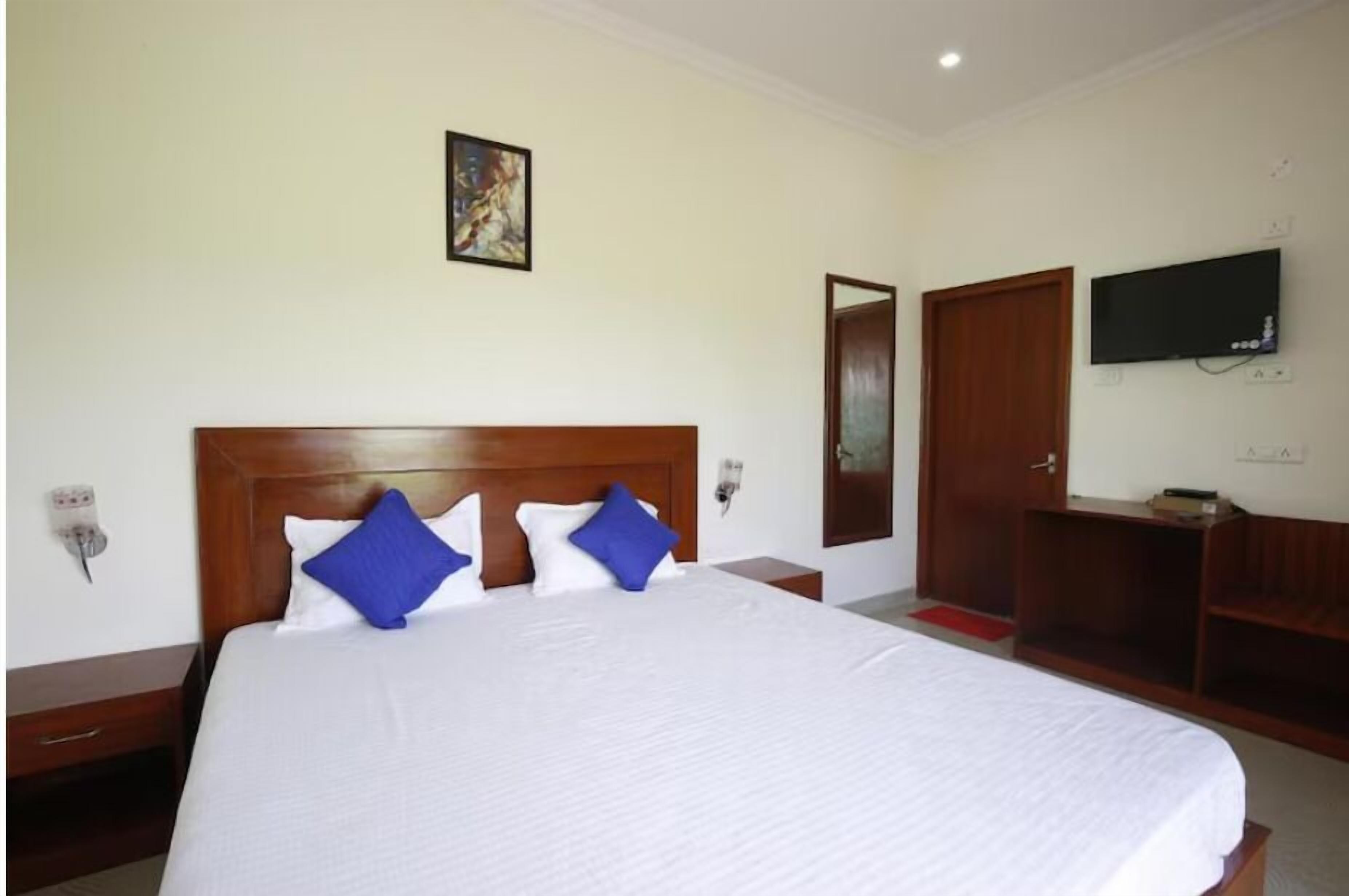 Quarto de hotel com uma cama grande, cabeceira de madeira, televisão de tela plana na parede e guarda-roupa de madeira.