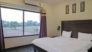 Habitación de hotel con una cama grande, una ventana con cortinas y vistas al exterior.