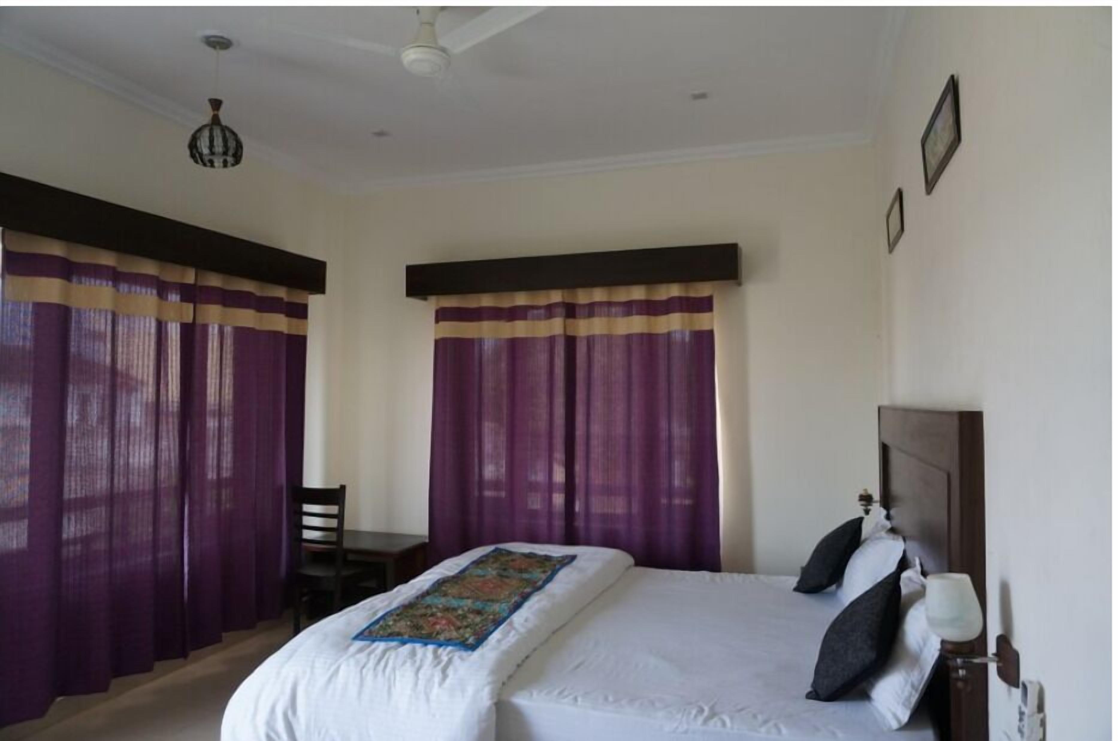 A hotel room with a bed, a chair, a desk, and a nightstand.