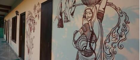Un pasillo con un mural de una mujer sosteniendo una olla y un niño, puertas y suelo de mármol.
