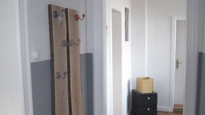 A hallway with wooden flooring, white walls, and a door with a wooden panel.