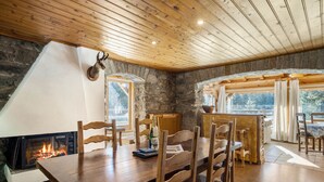 Un'accogliente zona pranzo con tavolo e sedie in legno, una parete in pietra e un camino.