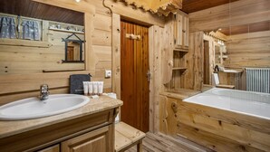Un bagno in stile baita con due lavandini, uno specchio e una vasca da bagno.