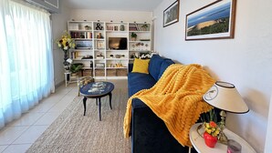 Ein Wohnzimmer mit einer Couch, einem Couchtisch, einem Bücherregal und einem Fernseher.